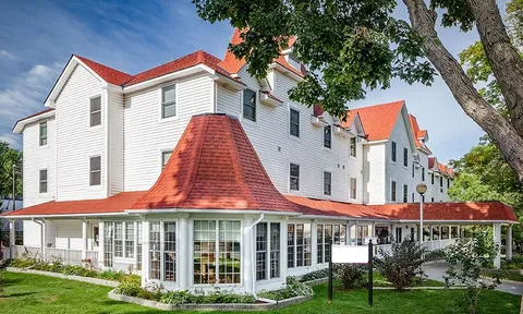 White residence with red roofs and wraparound ground floor windows