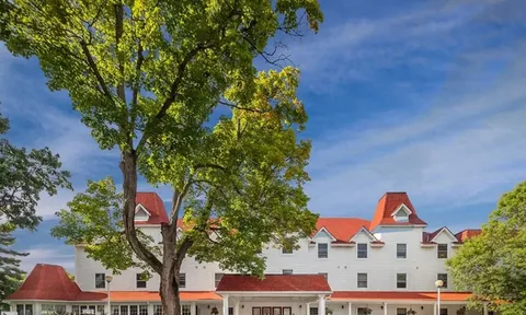Residence facade and red roofs behind a leafy tree