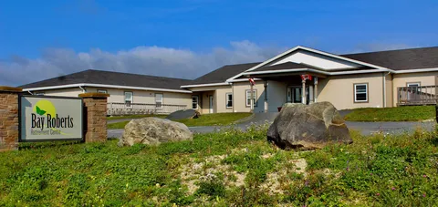 Low-rise residence with a covered entrance, lawn and large rocks.
