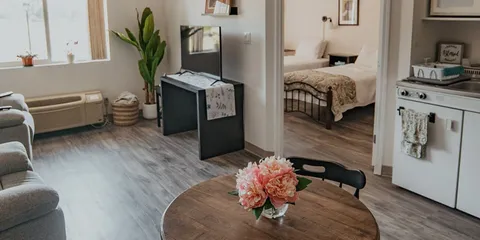 Suite living area with kitchenette, bedroom doorway and seating.