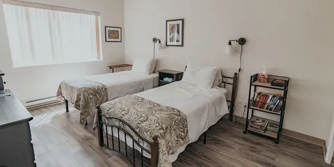 Bedroom with two single beds, bedside tables and a bookcase.