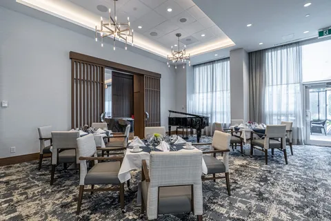 Dining room with set tables, upholstered chairs and a grand piano