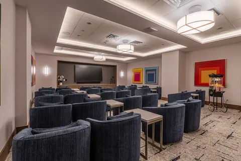 Rows of upholstered chairs facing a blank screen
