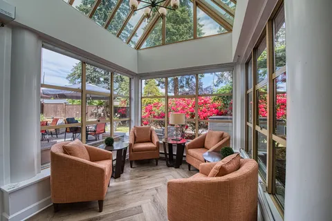 Sunroom with upholstered chairs, tables and windows.