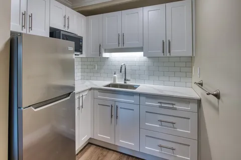 Kitchen with white cabinets, a sink and a refrigerator.