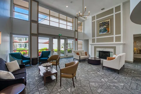 Lounge with upholstered chairs, a fireplace and tall windows.