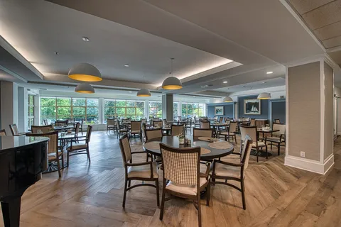 Dining room with wooden tables, chairs and large windows.