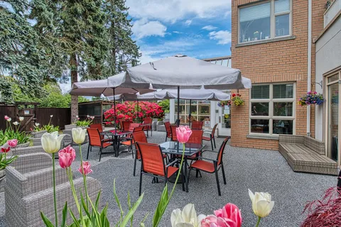 Patio with umbrella tables, chairs and flowering plants.
