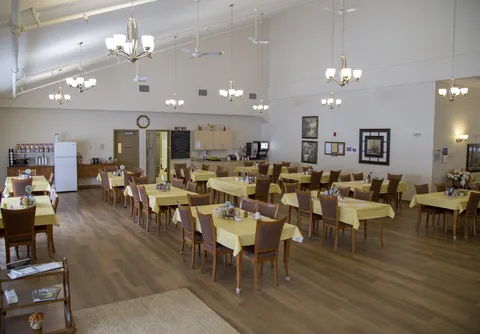 Wide dining-room view with yellow tablecloths and wood flooring.