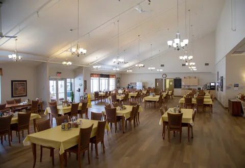 Dining room with set tables, ceiling fans and chandeliers.