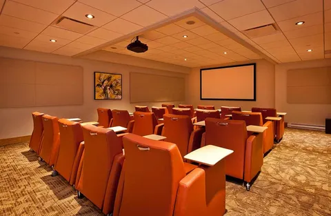 Theatre room with rows of orange reclining seats and a blank projection screen