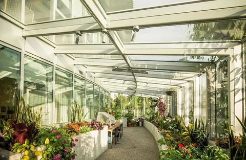 Glass-roofed garden room with planted beds and a central path