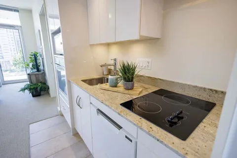 Kitchenette with white cupboards, a sink and an electric cooktop