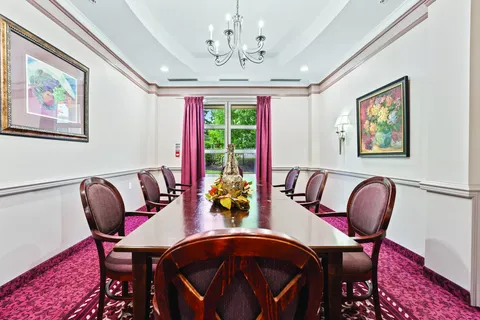 Dining room with a long wooden table and framed floral paintings