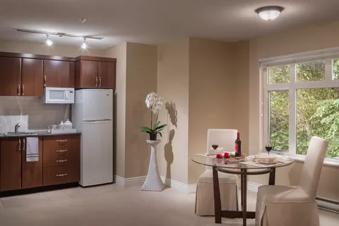 Kitchenette with wood cupboards beside a round dining table and window