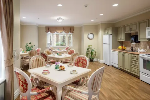 Room with round dining tables, upholstered chairs and kitchen cupboards