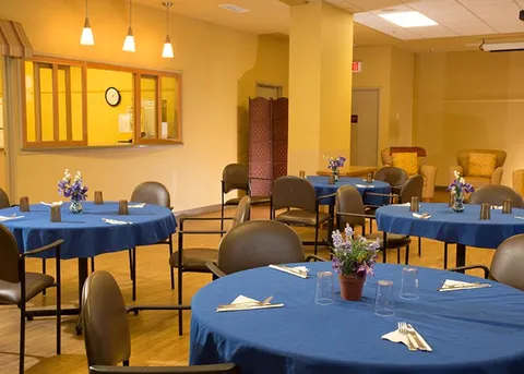 Dining room with round tables covered in blue cloths.