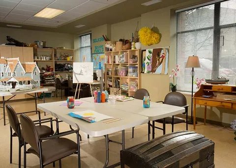 Activity room with work tables, craft supplies and shelving.