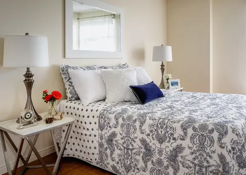 Bed with blue and white patterned bedding, bedside lamps and a mirror