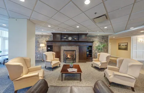 Armchairs around a wooden coffee table facing a fireplace in a stone wall