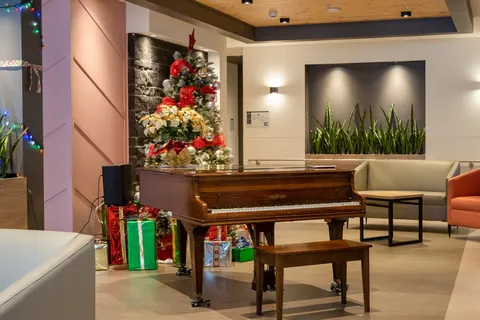 Piano and seating beside a decorated Christmas tree in the lounge.