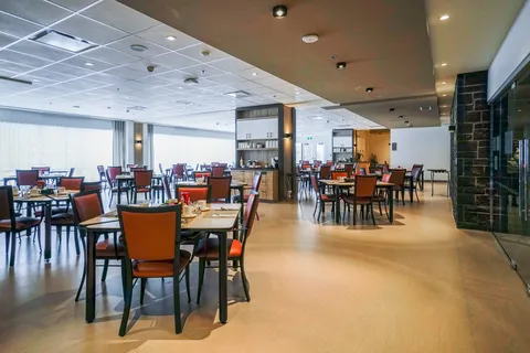 Dining room with tables, chairs and broad windows.
