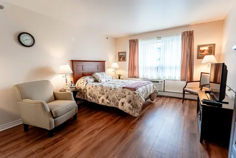 Bedroom with a double bed, armchair, lamps and a curtained window