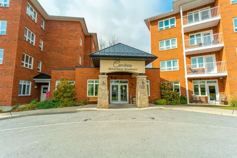 Covered brick and stone entrance with glass doors and a bench