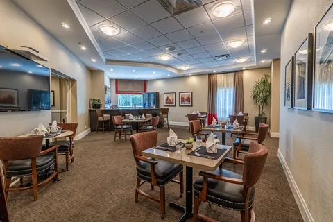 Dining room with set tables, upholstered chairs and a wall mounted television