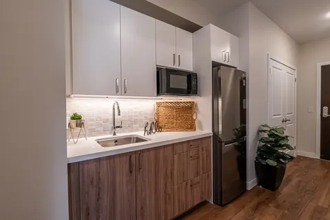 Kitchenette with white cabinets, a microwave, sink and refrigerator