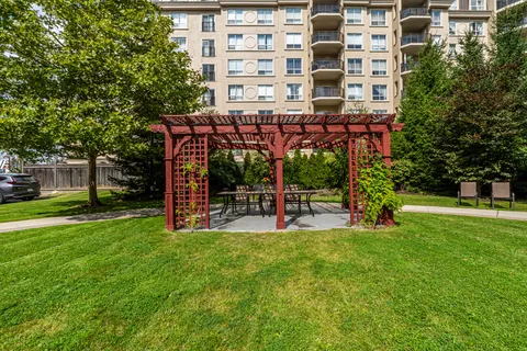 Garden with a wooden pergola, lawn and trees beside the residence