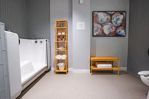 Bathroom with a walk in bath, shelving and folded towels