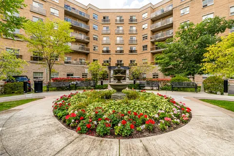 Courtyard with a fountain and flower beds surrounded by a brick residence