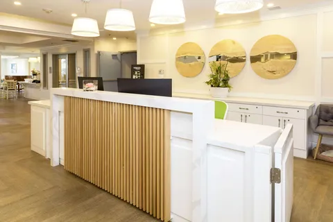 Reception desk with a white counter, pendant lights and circular wall mirrors