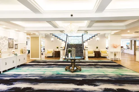 Lobby with a wide staircase, patterned rug, armchairs and a central table