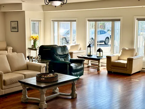 Lounge with leather sofas and armchairs beneath large windows.