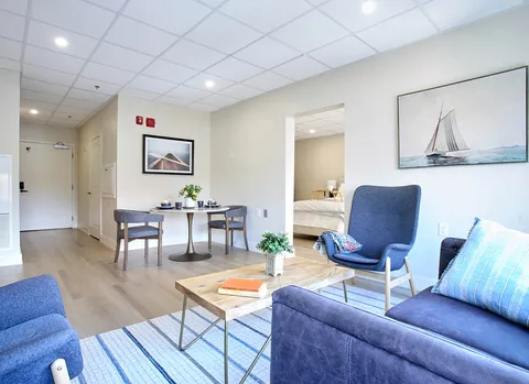 Sitting area with blue chairs, a sofa, coffee table and dining table