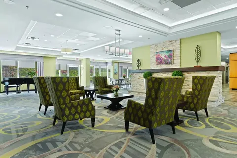 Armchairs around a stone fireplace with a piano beside the windows