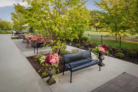 Garden path with a bench, flowering planters and patio tables