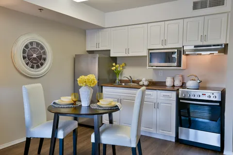 White kitchen cabinets and appliances beside a small round dining table