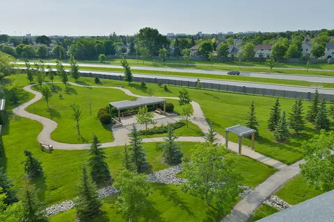 Landscaped lawn with winding paths, trees and covered seating