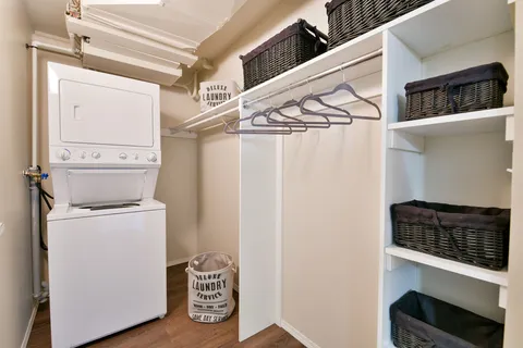 Laundry area with stacked washer and dryer, shelving and hanging space