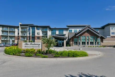 Residence with balconies, a covered entrance, landscaped beds and a stone sign
