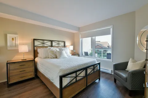 Bedroom with a wooden bed, nightstand, armchair and window