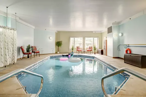 Small indoor pool with entry steps and chairs beside windows