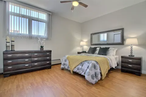 Bedroom with a made bed, dressers and a large wall mirror