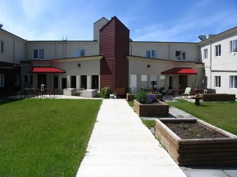 Residence exterior facing a courtyard with lawn and raised garden beds.