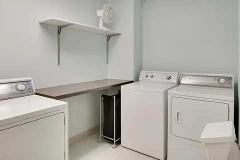 Laundry room with washing machines, a counter and wall-mounted fan