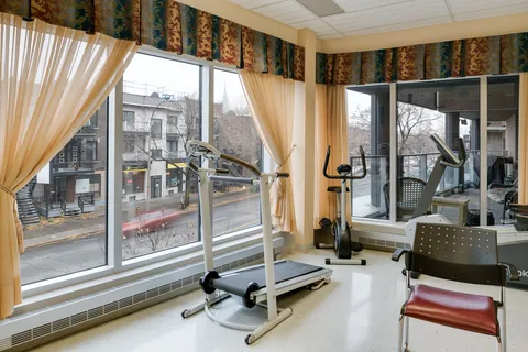 Exercise area with a treadmill, an exercise bicycle and large windows