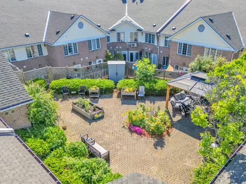 Enclosed courtyard with raised planting beds, chairs, a gazebo and flower beds